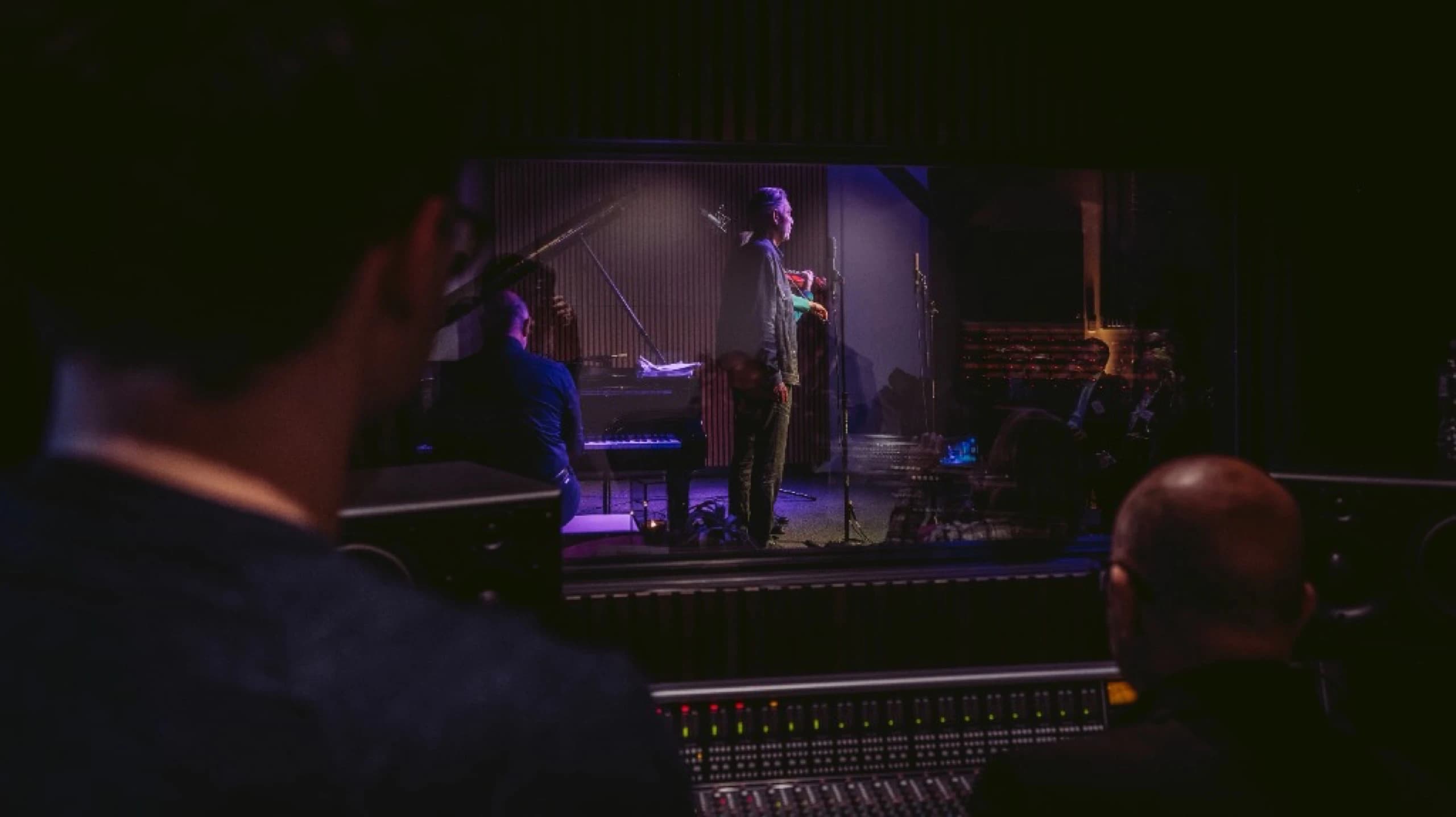 Performance space with stage and Persian rug, featuring dramatic lighting and wall-mounted guitars